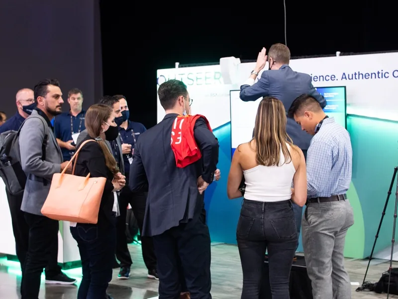 Attendees watching a performance at the Outseer booth.