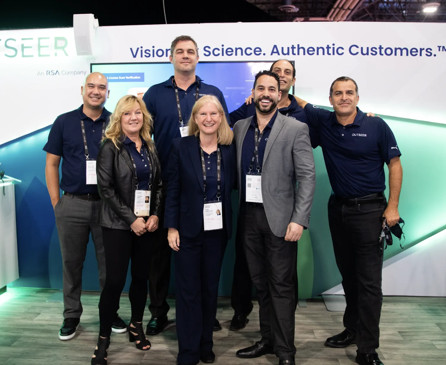 Outseer booth with a Showtime in Progress screen and Visionary Science, Authentic Customers messaging.