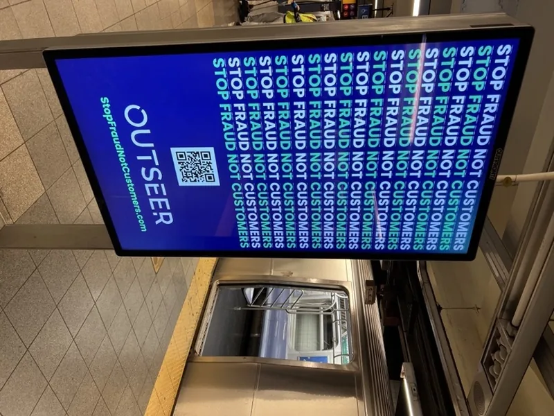 Outseer Stop Fraud Not Customers digital panel installed in a subway station.